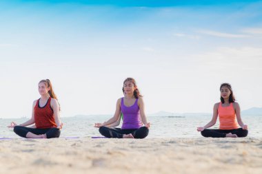 Yoga sınıf deniz Beach deki güneşli bir gün, bir grup insan lotu yapıyor