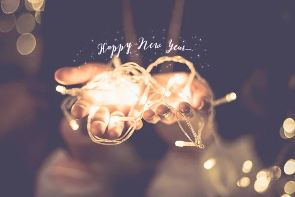 Feliz ano novo brilhando palavra sobre mão com luz do partido corda b — Fotografia de Stock