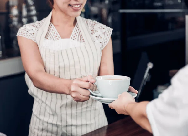 Barista servido café quente para o cliente com rosto sorridente na contagem — Fotografia de Stock