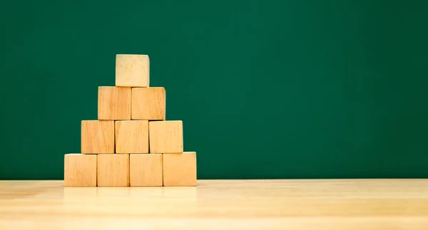 Pyramid shape build from wood cube on wooden table with green bl — Stock Photo, Image