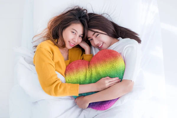 Asia lesbian LGBT Couple lay on bed and hug rainbow color pillow