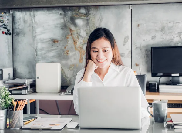 Asiatische Geschäftsfrau blickt auf Laptop-Computer und lächelt — Stockfoto