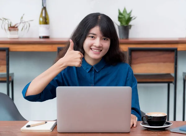 Asien kvinna freelancer tummen upp och leende använder laptop med kaff — Stockfoto