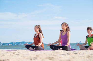 Yoga sınıf deniz Beach deki güneşli bir gün, bir grup insan lotu yapıyor