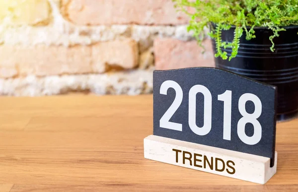 New year 2018 trends on blackboard sign and green plant on wood — Stock Photo, Image