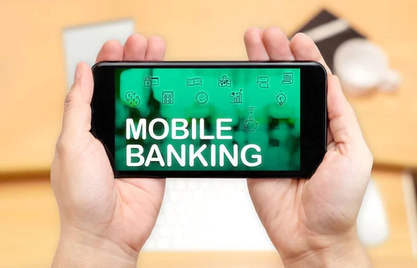 Смотреть, как две руки держат мобильный телефон со словом Mobile banking — стоковое фото