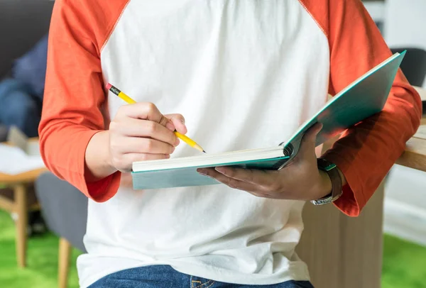 Close up a Giovane ragazzo adolescente che scrive su notebook blu a Bilancia — Foto Stock