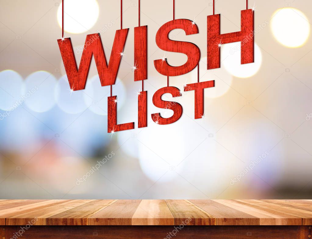 Wish list word hanging over wood table with blurred abstract bok