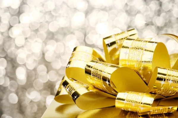 Close up Golden present box with big bow at bokeh white blur bac