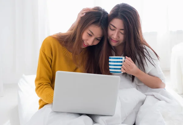 Asia lesbica lgbt coppia seduta sul letto abbraccio e utilizzando computer portatile com — Foto Stock