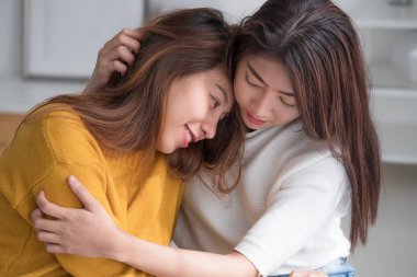 Asya lezbiyen lgbt çift sarılmak ve yatakta beyaz windo yakın oturan