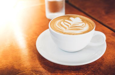 Beyaz kahve fincanı ile kalp şekli latte sanat ahşap sekmesinde yukarı kapatın