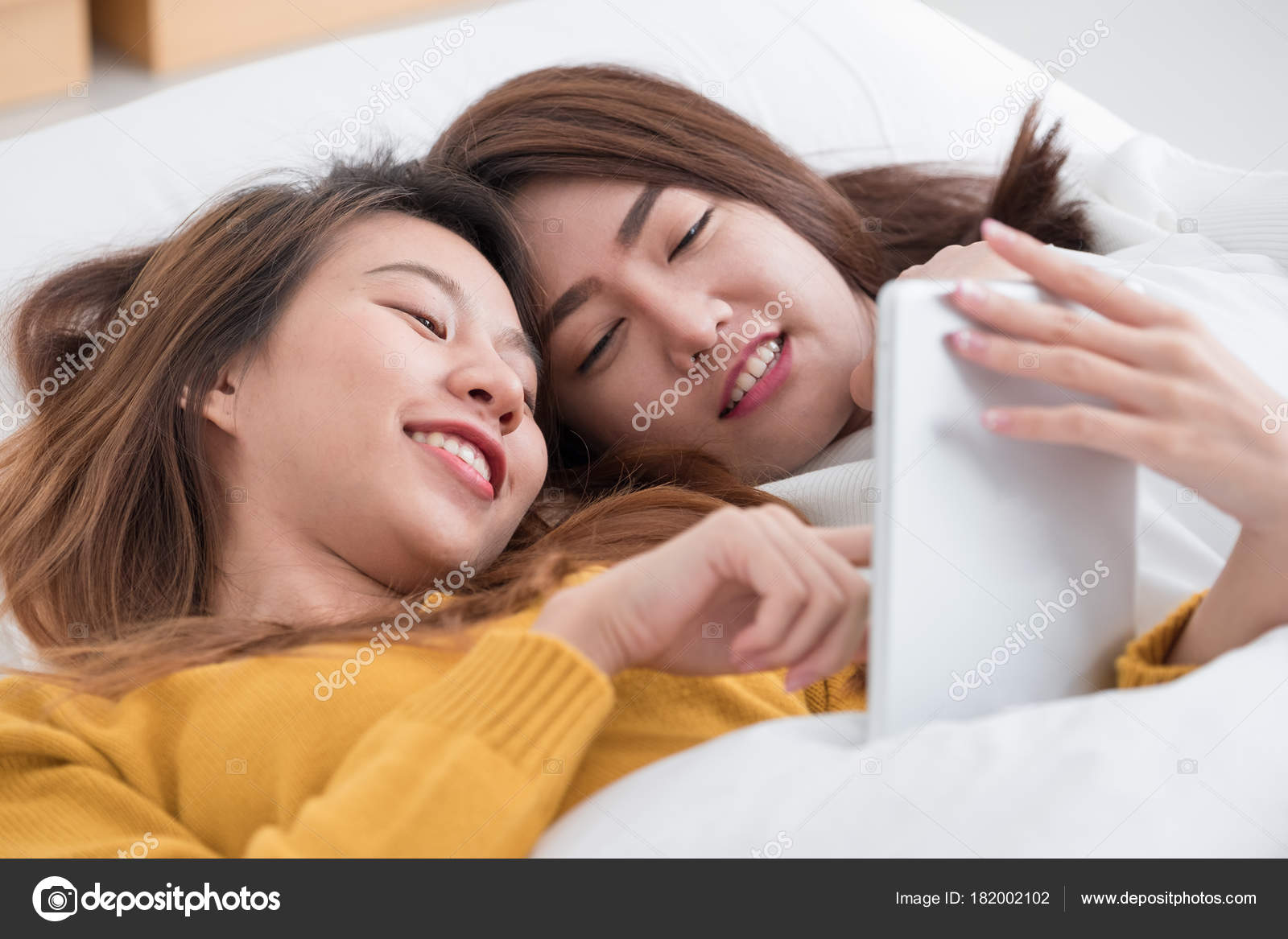 Asia lesbian lgbt couple lying on bed using tablet together in b Stock Photo by ©weedezign 182002102