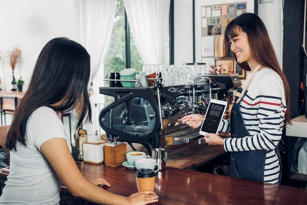 Mulher asiática barista desgaste jean avental sugestão menu de café para cu — Fotografia de Stock