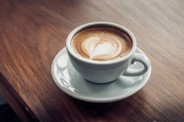 Cerrar taza de café capuchino caliente con forma de corazón arte latte en — Foto de Stock