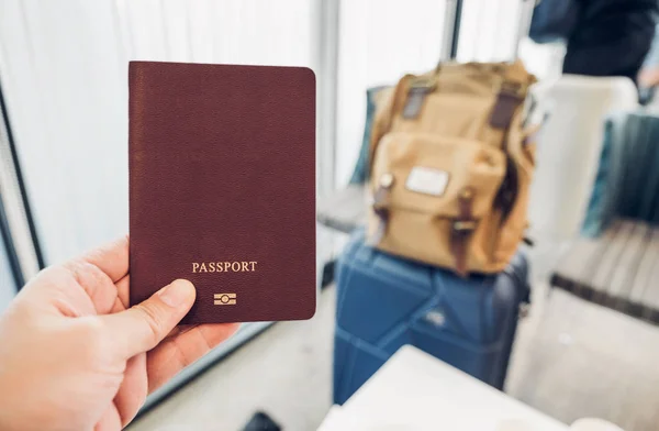 Primer plano mano celebración de pasaporte en la terminal del aeropuerto con maleta — Foto de Stock