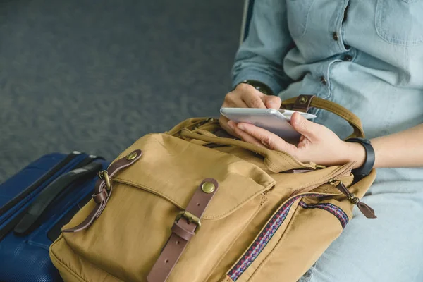 Mano de mujer de cerca usando el teléfono móvil con la mochila y las suitcas — Foto de Stock