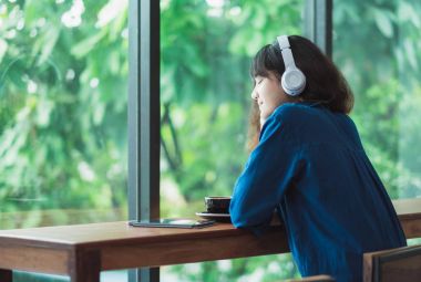 Mutlu Asyalı casual kadın yakınındaki kablosuz kulaklık ile müzik dinleme