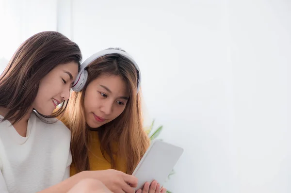 Due asiatico donna godere ascolto musica app su tablet seduta su così — Foto Stock