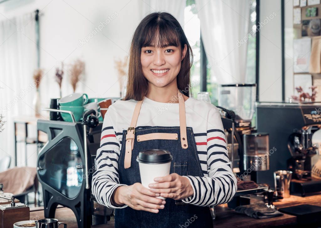 asian woman barista wear jean apron holding hot take away coffee