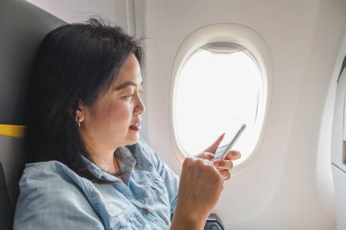 Asyalı kadın pencerede otururken uçakta koltuk ve airpl üzerinde açmak