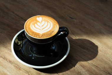 Sıcak siyah kahve fincanı ile ağaç kalp şekli latte sanat mi kapatın