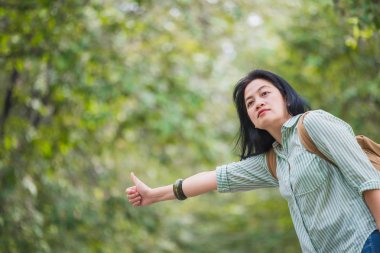 Asyalı kadın backpacker ağacında ile kırsal yolda duran