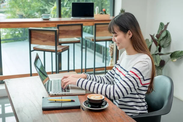 Felice donna asiatica utilizzando sul computer portatile mentre si lavora vicino wi — Foto Stock