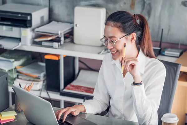 Asiatiska affärskvinna talar på mobiltelefon framför laptop c — Stockfoto