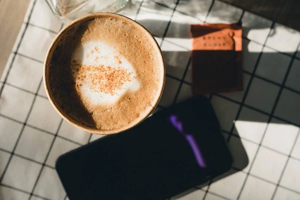 Cappuccino w zabrać filiżankę kawy z telefonu tabela cl — Zdjęcie stockowe