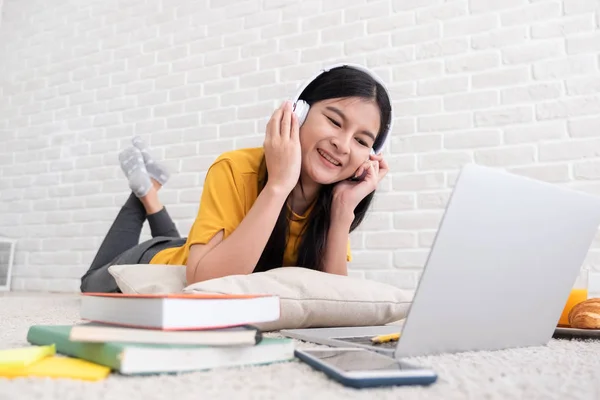 Asyalı kadın müzik dinlemek ve çalışmak için dizüstü bilgisayar kullanarak — Stok fotoğraf