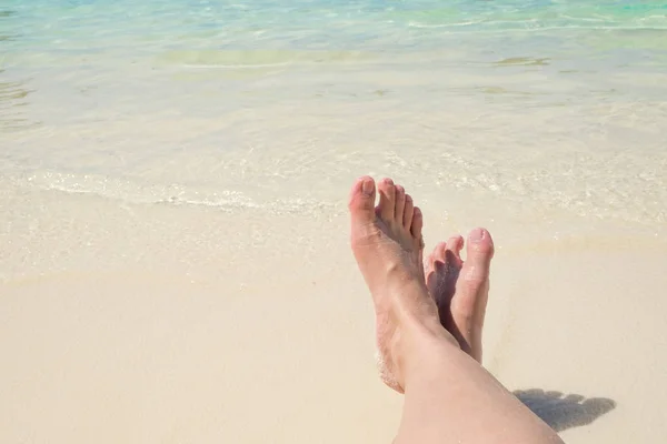 Bliska podróżnik krzyż boso nóg leżąc na plaży na morzu shor — Zdjęcie stockowe