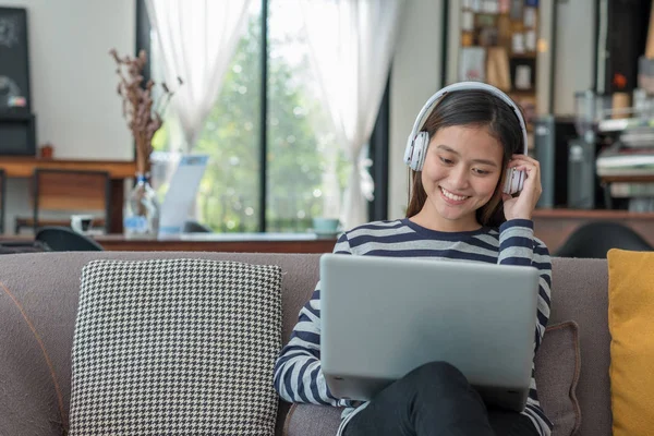 Dizüstü bilgisayar kullanan ve müzik dinlemek üstünde Asyalı genç kız — Stok fotoğraf