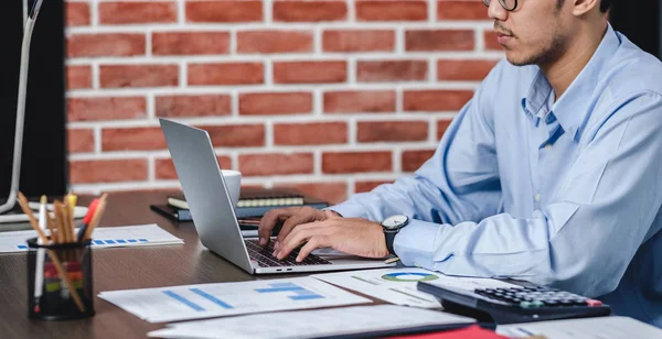 Asiatischer Geschäftsmann wacht mit Laptop und Papierkram am Schreibtisch auf — Stockfoto