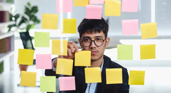 Ásia empresário olhando e escrevendo no pegajoso nota para brainst — Fotografia de Stock