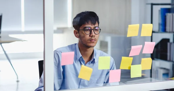 Азиатский бизнесмен ищет и пишет на липкой ноте для мозгов — стоковое фото