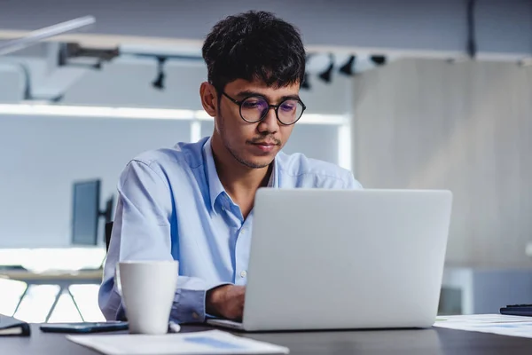 Asiatischer Geschäftsmann wacht mit Laptop und Papierkram am Schreibtisch auf — Stockfoto