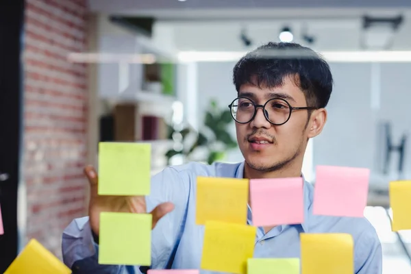 Азиатский бизнесмен ищет и пишет на липкой ноте для мозгов — стоковое фото