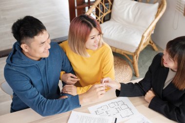 Asyalı mutlu çift yeni evinde gülen yüzlü emlakçıyla anahtar ve tokalaşma hakkı kazanıyor. Yeni bir ev satın alıyorlar.