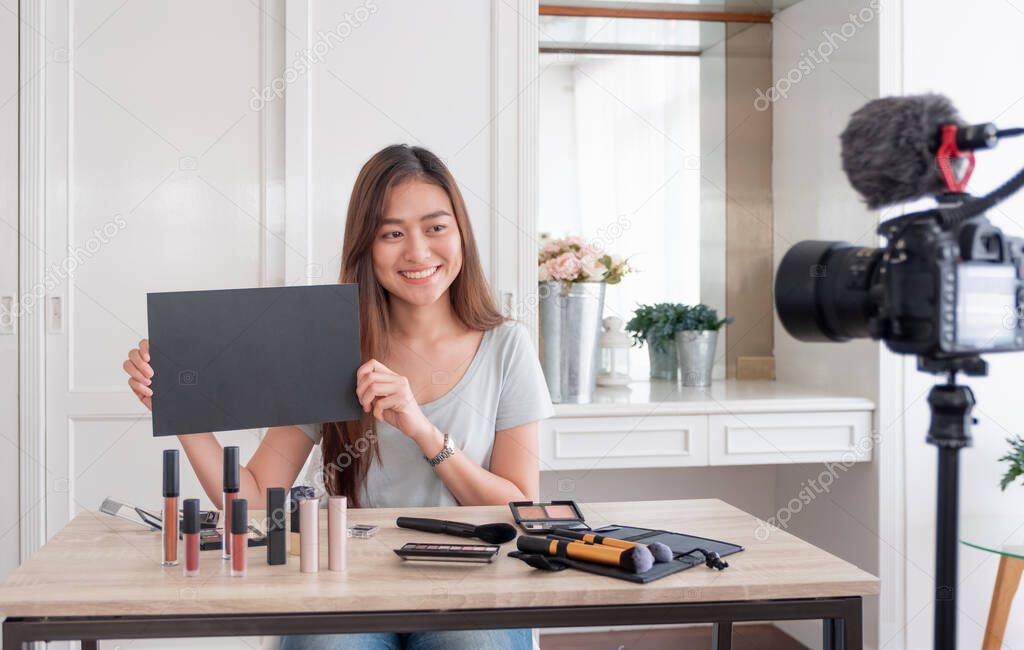 Asian young female blogger giveaway gift fan following channel while recording vlog video with makeup cosmetic at home online influencer concept.live streaming viral.mock up blackboard for your design