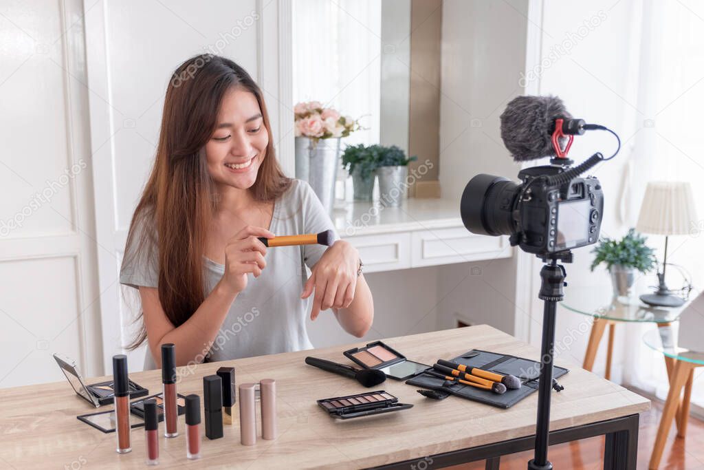 Asian young female blogger recording vlog video with makeup cosmetic at home online influencer on social media concept.live streaming viral 