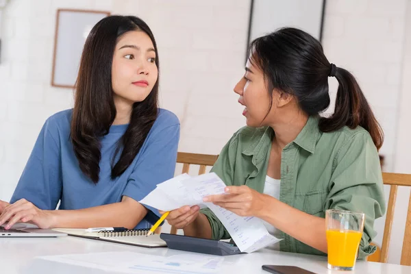Stressed Asian lesbian couple serious and argument when calculate home financial bill budget on table in kitchen at new house