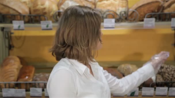 女卖家从货架上拿黑面包 — 图库视频影像