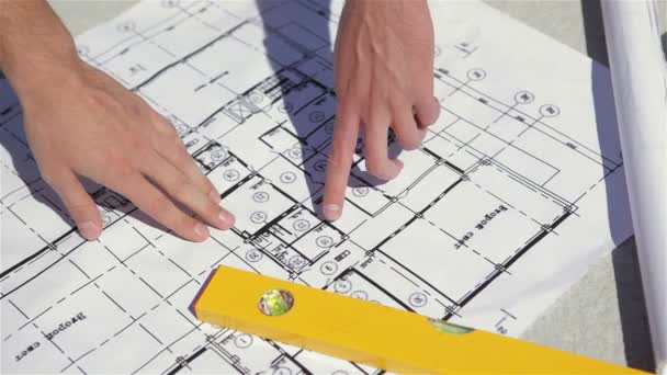 Мужские пальцы указывают на план строительства здания — стоковое видео