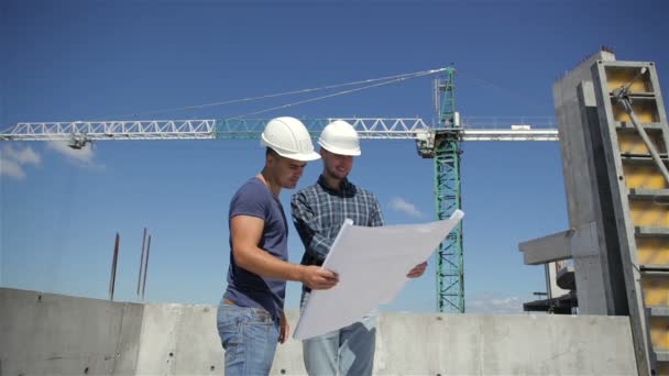 Gerente de construcción señala el plan de construcción en construcción — Vídeos de Stock