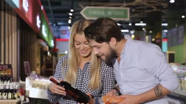 Junges Paar wählt Wein im Supermarkt — Stockvideo