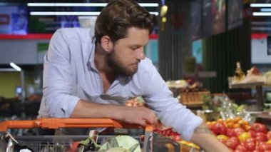 Adam alışveriş merkezinden domates ve salatalık alıyor.