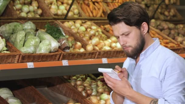 Un homme écrit dans son carnet au supermarché — Video