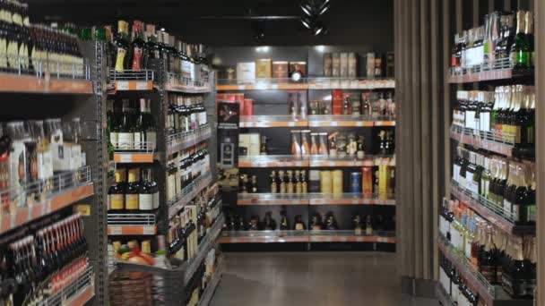 Couple walk through the alcohol section of hypermarket — Stock Video