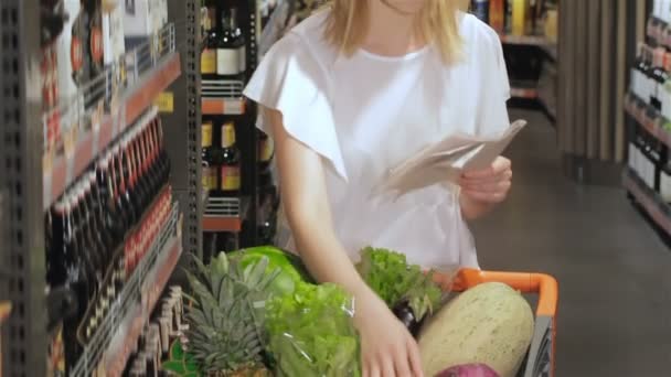 Girl kontrollerar listan över produkter att köpa — Stockvideo